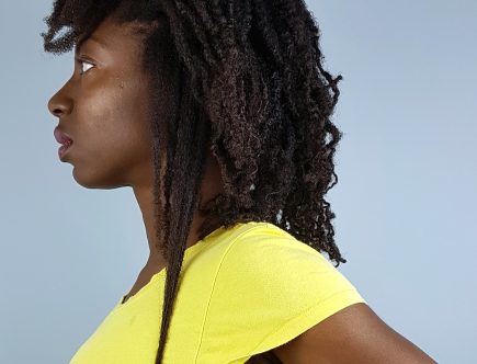 Girl standing in profile pulling a section of her hair straight