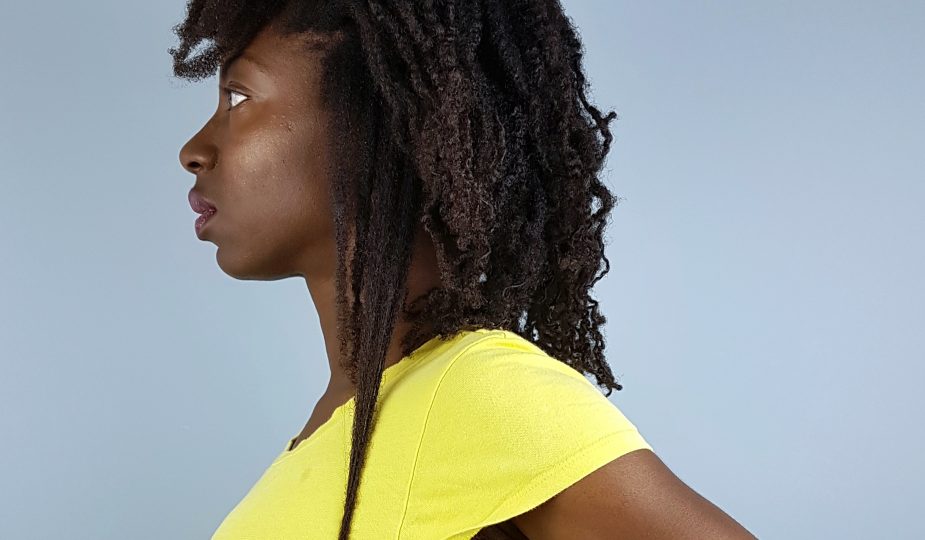 Girl standing in profile pulling a section of her hair straight